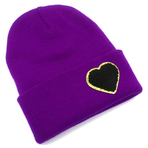 Detail of purple ribbed knit beanie featuring a black heart patch with gold glitter edge