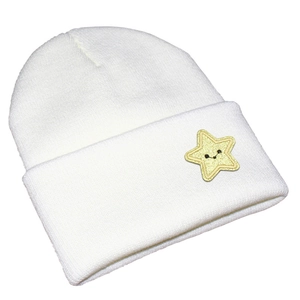 Close-up of white knit beanie featuring a yellow star patch with cute expression detail