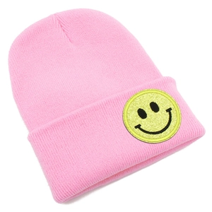 Gros plan sur un bonnet en tricot rose avec un patch smiley jaune pailleté décoratif