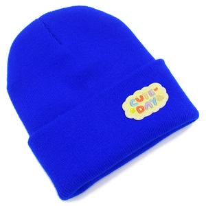 Détail du bonnet en maille bleu avec broderie Cute Day sur le revers plié du vêtement