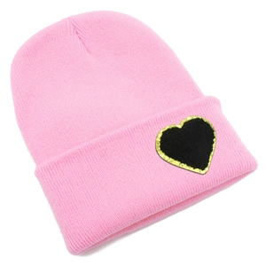 Detail shot of the pink knit beanie featuring a black heart patch with gold glitter edges
