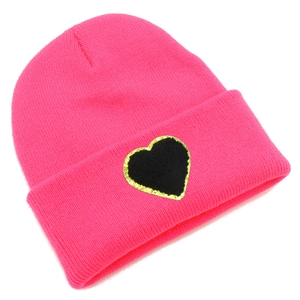 Close-up detail of knitted texture and black heart patch on hot pink winter beanie hat