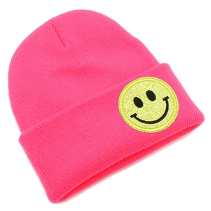 Détail d'un bonnet en tricot rose avec un patch smiley jaune scintillant décoratif