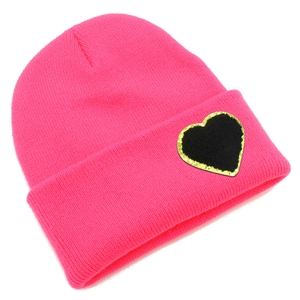 Close-up of pink knit beanie with black heart patch and gold sequin accents