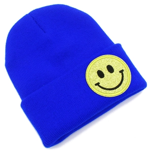 Détail du bonnet en maille bleu avec un patch écusson smiley en paillettes jaunes