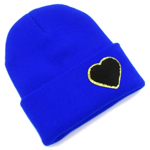 Detailed close-up of a blue knit beanie featuring a black heart patch with gold glitter edges