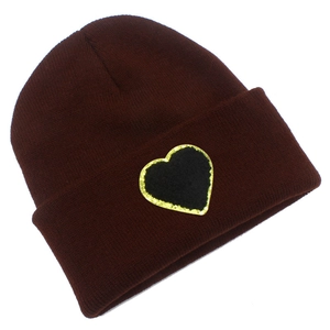 Detail of dark red knit beanie showing a black heart patch with gold glitter embroidery