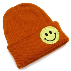 Détail du bonnet en tricot orange avec écusson smiley jaune cousu pour un look très tendance