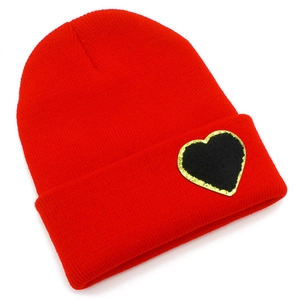 Detailed view of red knitted beanie with gold glitter heart patch and folded brim