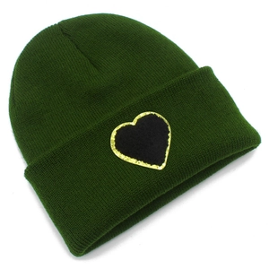 Detail of dark green knit beanie featuring a black and gold sequin heart patch