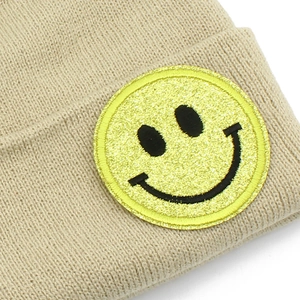 Bonnet en tricot beige avec un écusson smiley jaune scintillant pour un look d'hiver