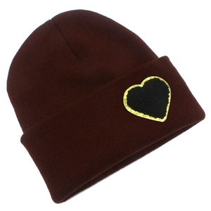 Detailed view of dark burgundy knit beanie with black sequined heart patch on the cuff
