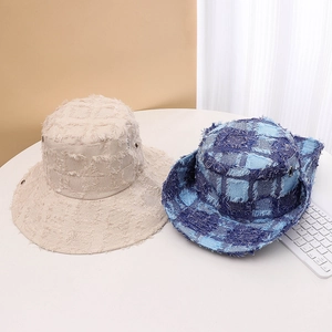 Detail view of casual frayed bucket hats in beige and blue plaid for outdoor sun protection.