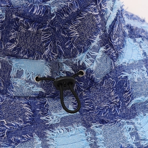 Close-up detail of blue distressed denim bucket hat with adjustable black elastic drawstring.