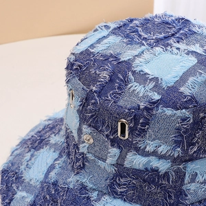 Denim bucket hat close up detail showing patchwork frayed design with metal eyelets.