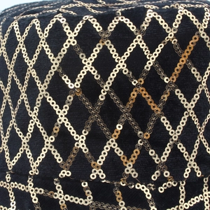 Gros plan de paillettes dorées en motif de losange sur le tissu noir d'un bob chic
