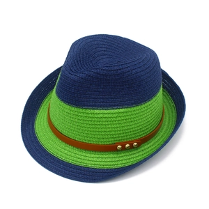 Detail of contrast color woven straw fedora hat featuring a brown leather studded band