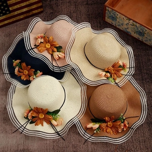 Detail showing colorful straw sun hats with wavy brims and floral side decorations