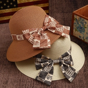Elegant woven sun hats with 'HAPPY' printed ribbon bows in brown and beige colors