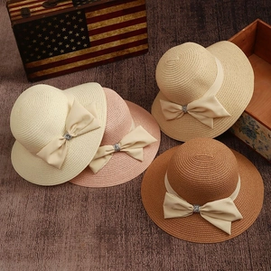 Detail of four sun hats in cream, pink, and khaki with ribbon bows and rhinestones