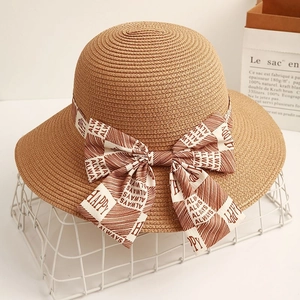 Elegant straw sun hat with ribbon bow featuring Happy letters on a stylish white basket