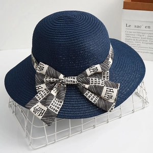 Detail of navy blue straw sun hat featuring a striped bow with HAPPY and ALWAYS text