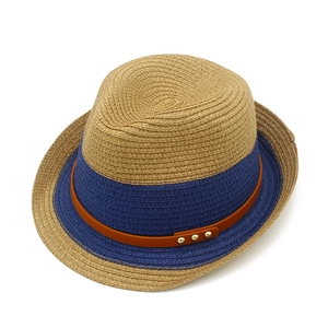 Detailed close-up of woven fedora hat with navy band, leather strap and gold metal rivets