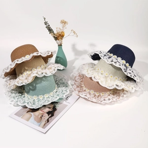 Top view of woven straw hats with lace edges and daisy details in various colors