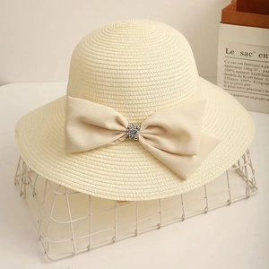 Elegant wide brim straw sun hat for women with a cream ribbon bow and rhinestone detail