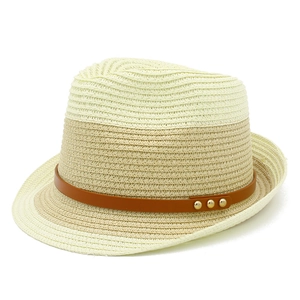 Detail of two-tone straw sun hat with brown leather band and gold metal studs