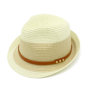 Macro detail of bicolor straw hat texture with brown faux leather band and gold metal studs