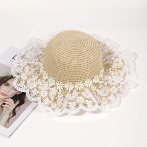 Detailed macro view of the beige woven straw hat with lace brim and small white daisies