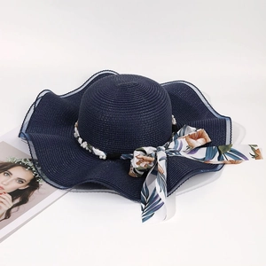Détail d'un chapeau de paille à bord bleu marine avec perles et ruban à fleurs chic