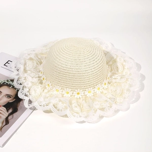 Detailed view of women's woven straw sun hat with lace brim and small daisy floral accents