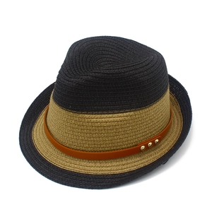 Detail of two-tone woven straw hat with brown leather band and gold metal studs