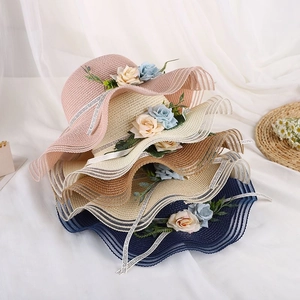 Detail of colorful wide-brimmed straw hats with wavy edges and artificial flowers