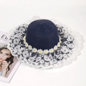 Navy blue woven straw sun hat featuring elegant white lace brim and daisy flower accents