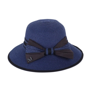 Dettaglio di un cappello di paglia blu scuro con fiocco marrone e decorazione a lettera M