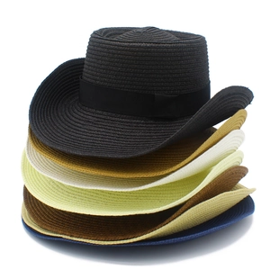 Close-up of stacked woven straw cowboy hats in various colors with black ribbon bands