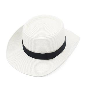Close-up of the woven texture and black ribbon on a white paper straw boater hat