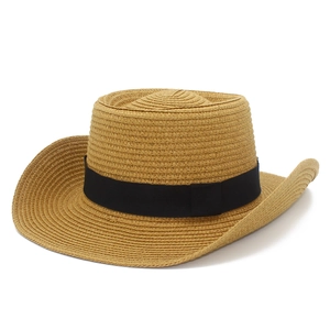 Detail of hand-woven straw cowboy hat with black decorative ribbon and curved brim