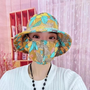 Dettaglio di cappello da sole giallo con stampa tropicale e maschera protettiva UV abbinata