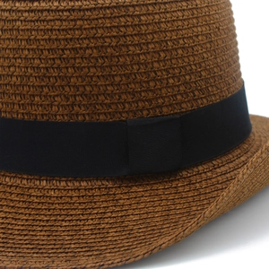 Detailed macro view of brown woven straw hat texture with a wide black grosgrain ribbon