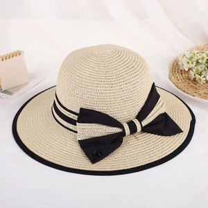 Beige straw sun hat with black ribbon, bow detail, and a metallic letter M accent
