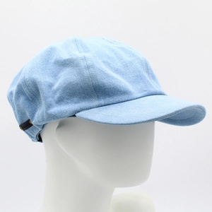 Detail view of the light blue washed denim newsboy cap with side logo label on mannequin