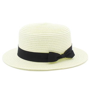 Dettaglio del cappello di paglia con nastro di gros grain nero e fiocco su sfondo bianco