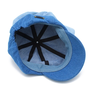 Detail view of denim octagonal hat interior showing black support strip and leather tag