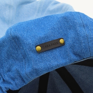 Detail of blue denim fabric with leather brand tag and vintage brass metal rivets