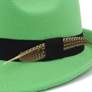 Close-up of bright green wool fedora hat featuring black ribbon and natural brown feather