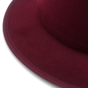 Detailansicht eines dunkelroten Fedora-Hutes mit feinen Nähten und Wollfilz-Struktur